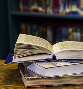 Open book on top of stacked books in a library