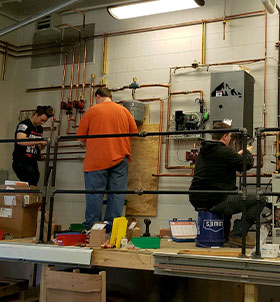 Three students on air conditioning units