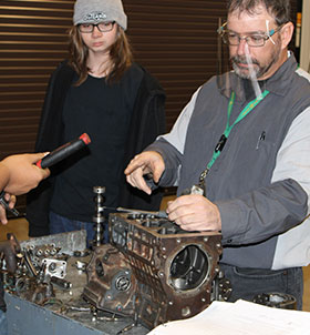 Students and teacher working on diesel engine